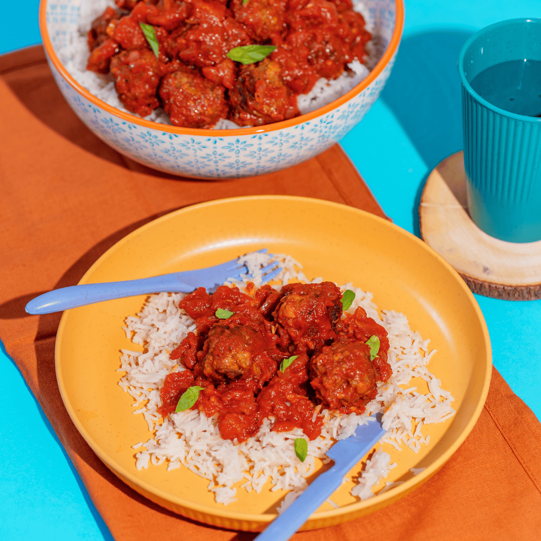 Vegetable beef meatballs served over rice with tomato sauce, colorful children's meal, healthy lunch option for preschool kids.