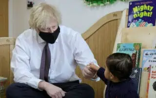 Engaging children's storytime at Monkey Puzzle Day Nurseries, with a teacher reading vibrant children's books and interacting with a young child in a welcoming reading corner.