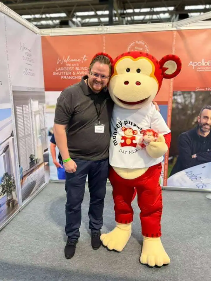 Monkey Puzzle Day Nurseries mascot with happy man at childcare event.