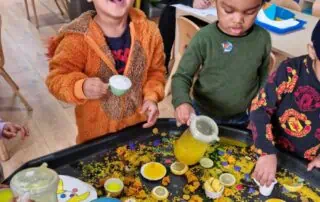 Bright-eyed young children enjoying sensory play with colorful lemon slices, confetti, and themed decorations at Monkey Puzzle Day Nurseries. A lively and engaging environment fostering early childhood development.