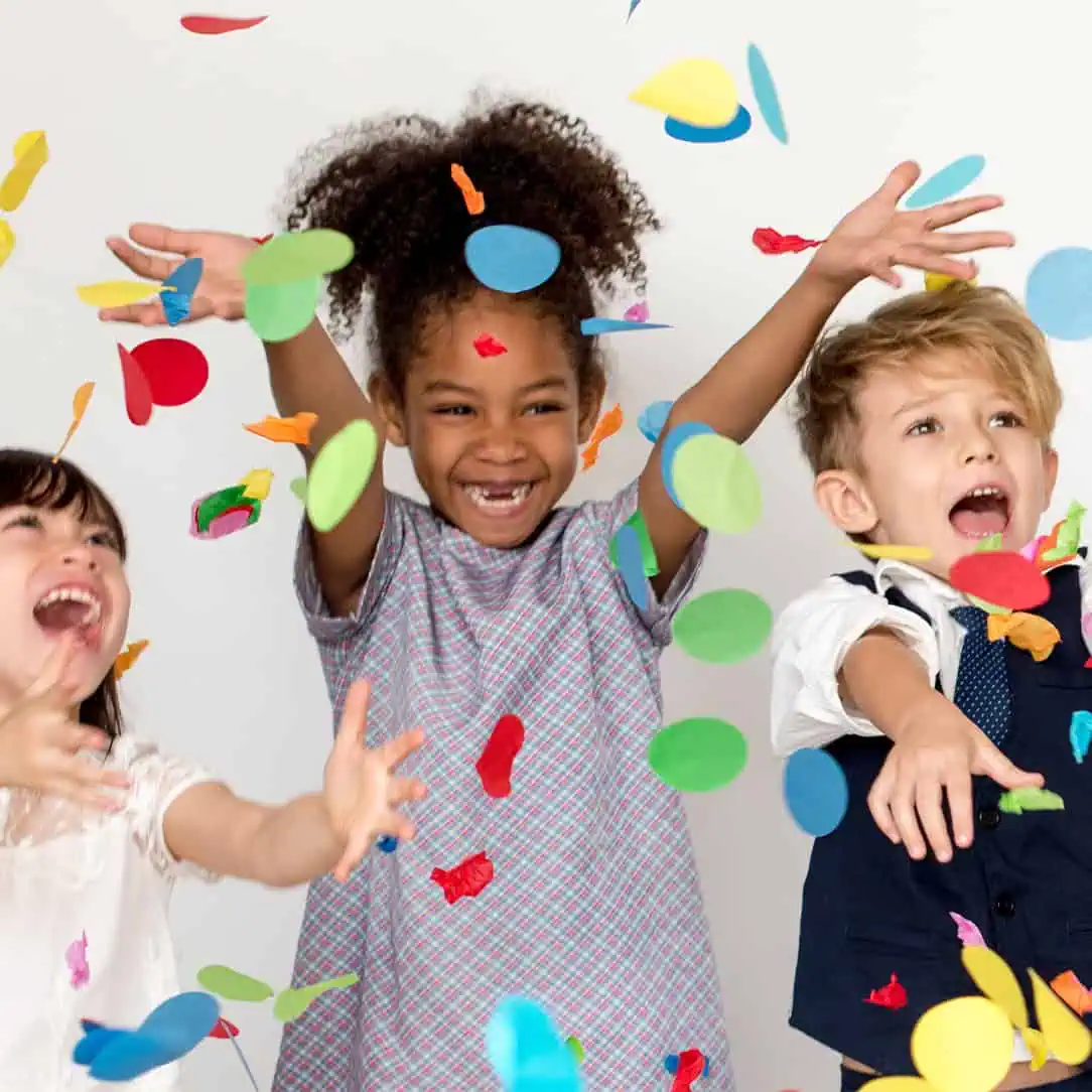 Colorful children celebrating with confetti at Monkey Puzzle Day Nurseries, showcasing a joyful and engaging early childhood environment.