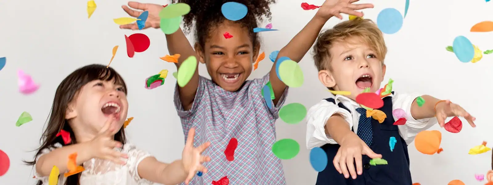 Colorful children playing with confetti at Monkey Puzzle Day Nurseries, showcasing a vibrant and engaging early childhood education environment.