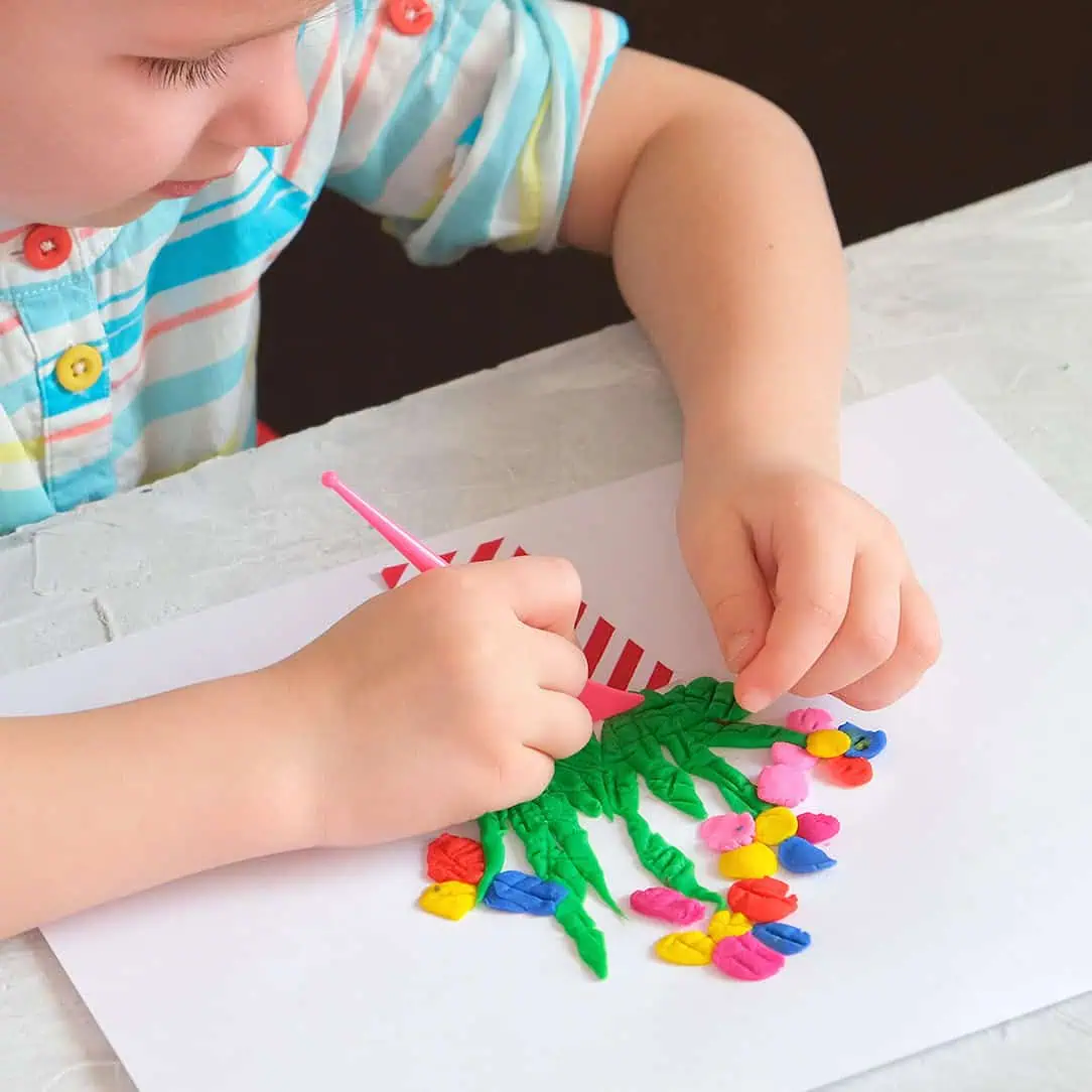 Vibrant child creating colorful artwork with clay and a pink tool at Monkey Puzzle Day Nurseries.
