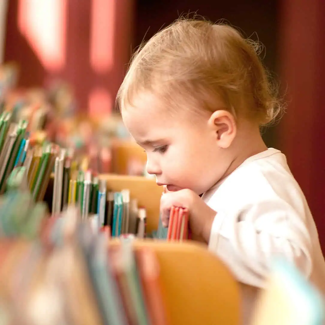 Young child exploring books at Monkey Puzzle Day Nurseries, fostering early literacy and development in a nurturing environment.