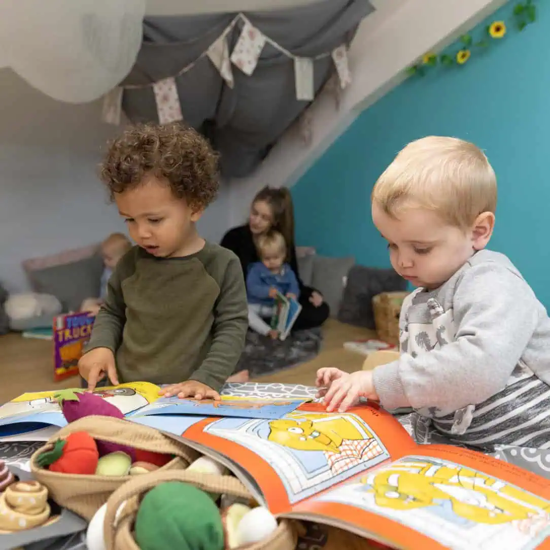 Colorful children's activity area at Monkey Puzzle Day Nurseries with kids reading books and engaging in playful learning activities in a cozy, child-friendly environment.