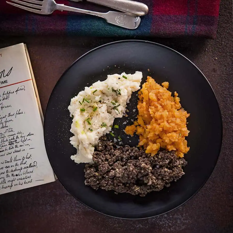 Creamy mashed potatoes with chopped chives, sweet mashed butternut squash, and seasoned ground beef on a black plate, served at Monkey Puzzle Day Nurseries, promoting healthy eating and nutrition for young children.
