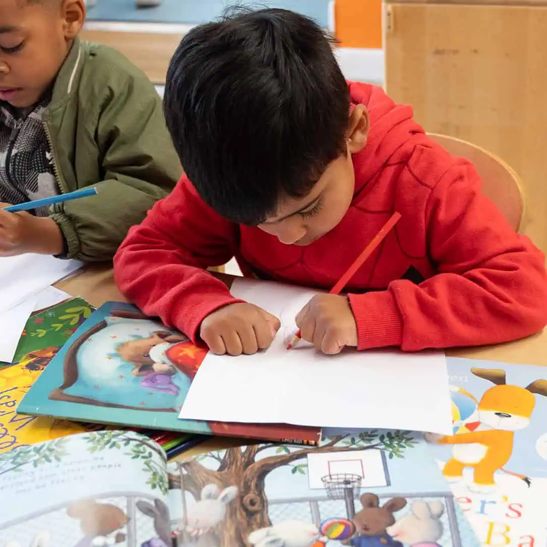 Children drawing and reading colorful picture books at Monkey Puzzle Day Nurseries, engaging preschoolers in creative learning activities, fostering early literacy and developmental skills.