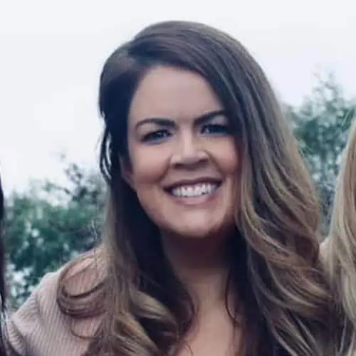 Jess McCarthy A smiling young woman with long brown hair outdoors at Monkey Puzzle Day Nurseries, emphasizing a welcoming environment for children's early education.