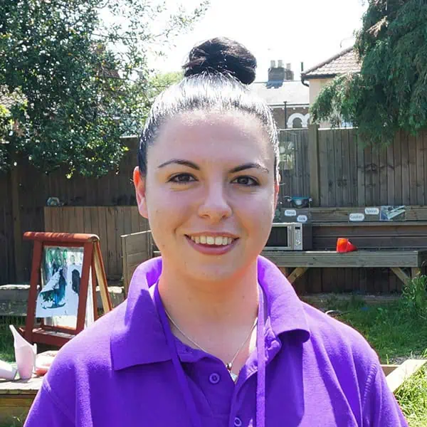Friendly childcare professional at Monkey Puzzle Day Nurseries, outdoor play area, engaging early childhood education, caring nursery staff for children's development.