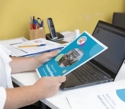 Brightly colored Monkey Puzzle Day Nurseries brochure being held in front of a laptop, showcasing early childhood education and childcare services for toddlers and preschoolers.