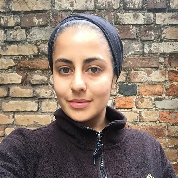 Friendly young woman with headscarf smiling outdoors, promoting Monkey Puzzle Day Nurseries and early childhood education.