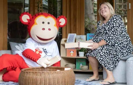 Marvin and Monkey Puzzle Guildford nursery manager Gina Monkey Puzzle Day Nurseries mascot, a cheerful monkey character, engaged with a caregiver during a creative activity outdoors, promoting joyful learning environments for children.