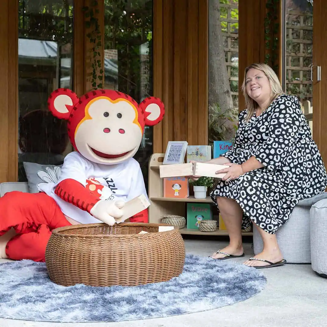 Marvin and Monkey Puzzle Guildford nursery manager Gina Monkey Puzzle Day Nurseries mascot, a cheerful monkey character, engaged with a caregiver during a creative activity outdoors, promoting joyful learning environments for children.