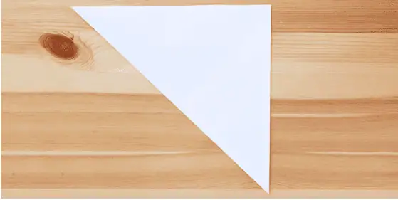 Paper snow flakes – Step 1 Empty white paper on wooden surface, symbolizing creativity and learning at Monkey Puzzle Day Nurseries.