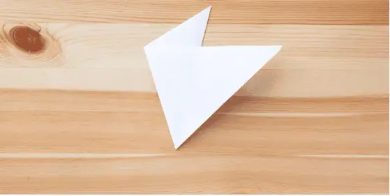 Paper snow flakes – Step 4 Colorful paper airplane on wooden surface, representing creativity and learning at Monkey Puzzle Day Nurseries.