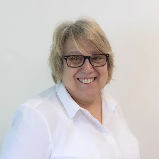 Friendly female day nursery staff member at Monkey Puzzle Day Nurseries, smiling in a white shirt, providing quality early childhood care and education.