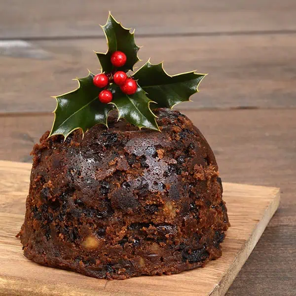 Chocolate Christmas pudding with holly berries and leaves, festive holiday dessert, traditional Christmas pudding, holiday treat, seasonal baked good, holiday celebration dessert, sweet Christmas dessert.