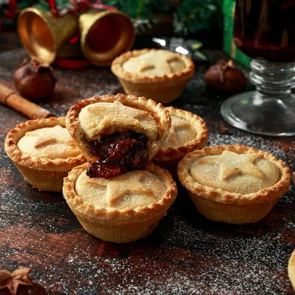 Mini Christmas mince pies with star-shaped pastry decorations on a rustic wooden surface, festive holiday treats perfect for children's celebrations at Monkey Puzzle Day Nurseries.