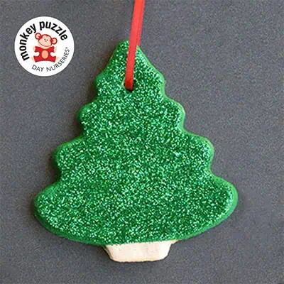 Colorful Christmas tree-shaped cookie decorated with green glitter frosting, perfect for holiday festivities at Monkey Puzzle Day Nurseries.