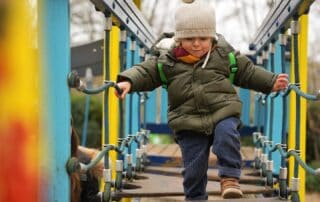 Colorful outdoor playground at Monkey Puzzle Day Nurseries, featuring young children engaging in active play and climbing activities that promote early childhood development.