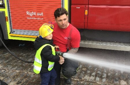 Fireman showing off fire service equipment with children
