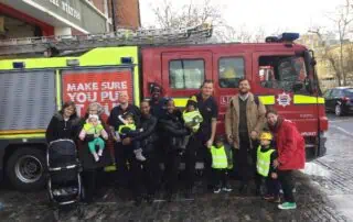 Children and staff from Monkey Puzzle Day Nurseries visiting a fire truck with firefighters for a community safety day, promoting early learning and safety awareness for young children.