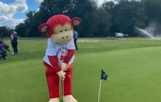 Happy mascot on the golf course at Monkey Puzzle Day Nurseries outdoor event, engaging children in fun activities and promoting active play in a safe, vibrant environment.