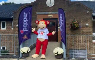 Cute monkey mascot outside Monkey Puzzle Day Nurseries supporting early childhood education and childcare services.