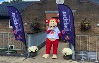 Colorful monkey mascot outside Monkey Puzzle Day Nurseries, supporting children's development and early education at the childcare facility.