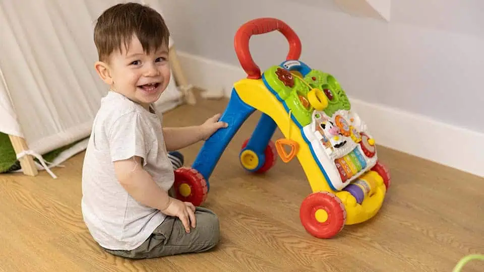 Toddler at play Bright smiling toddler playing with colorful walker activity toy at Monkey Puzzle Day Nurseries.