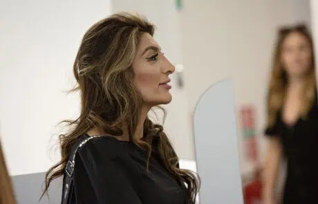 Great Place to Work for Women (3) Beautiful woman with long, wavy hair looking in a mirror at Monkey Puzzle Day Nurseries, showcasing a nurturing environment for young children.
