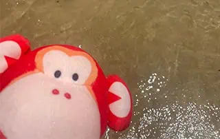 Marvin-in-Hawaii Colorful plush monkey toy floating in water at Monkey Puzzle Day Nurseries, creating a playful and engaging environment for young children.