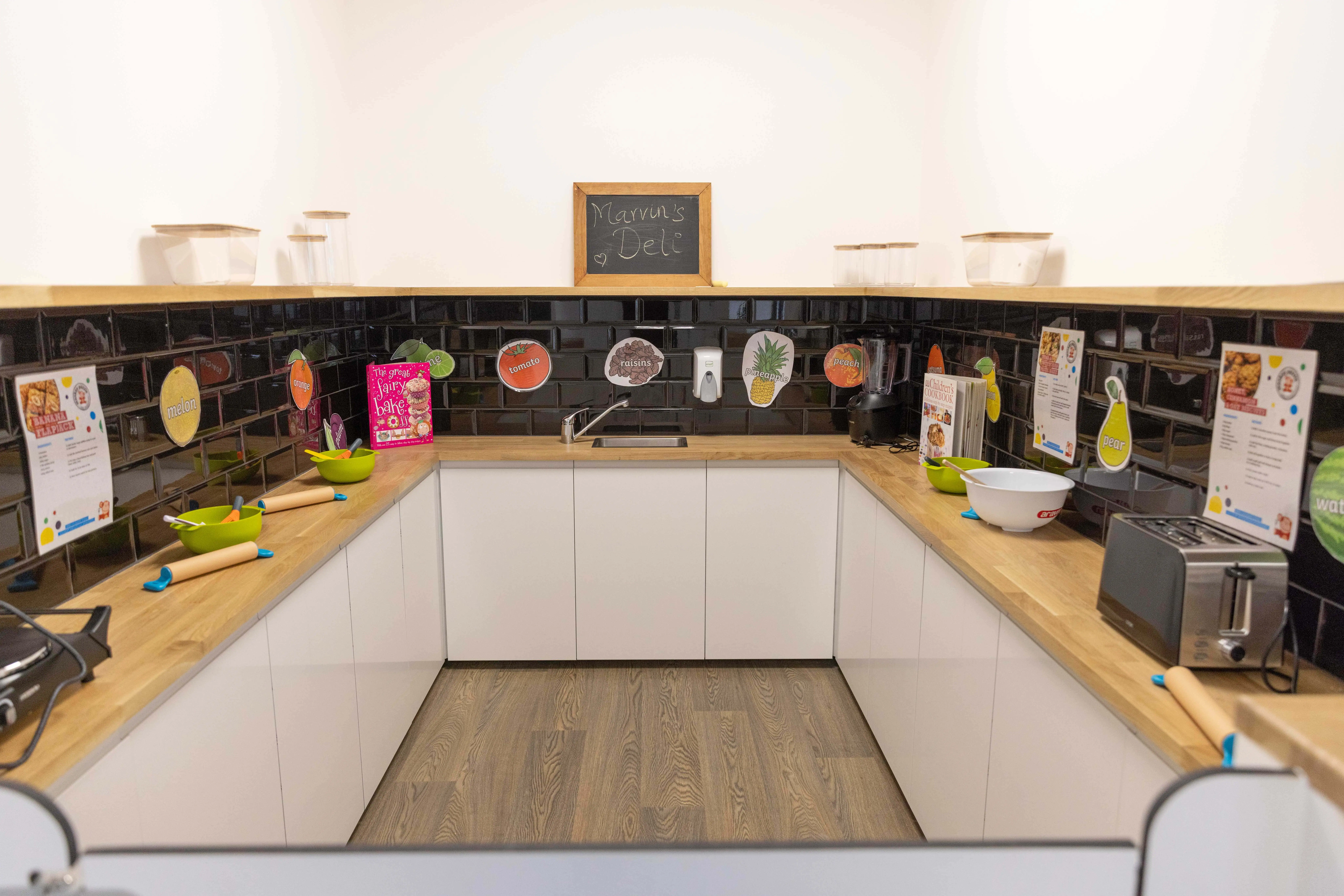 Children’s play kitchen and pretend cooking area in a colorful nursery setting, promoting early childhood development and imaginative play at Monkey Puzzle Day Nurseries.