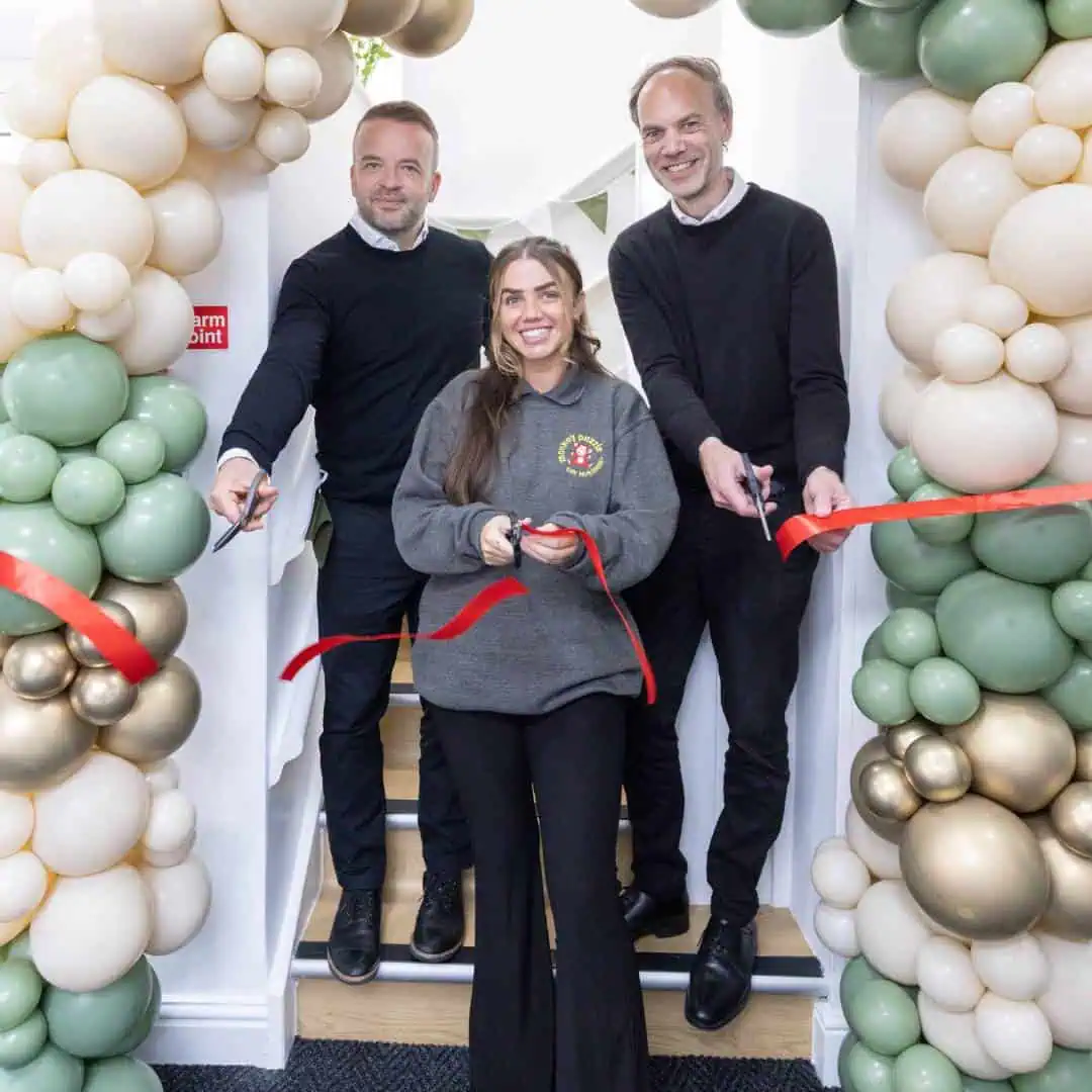 Colorful balloon arch decoration at Monkey Puzzle Day Nurseries opening event, featuring happy staff and teachers celebrating the new nursery establishment.