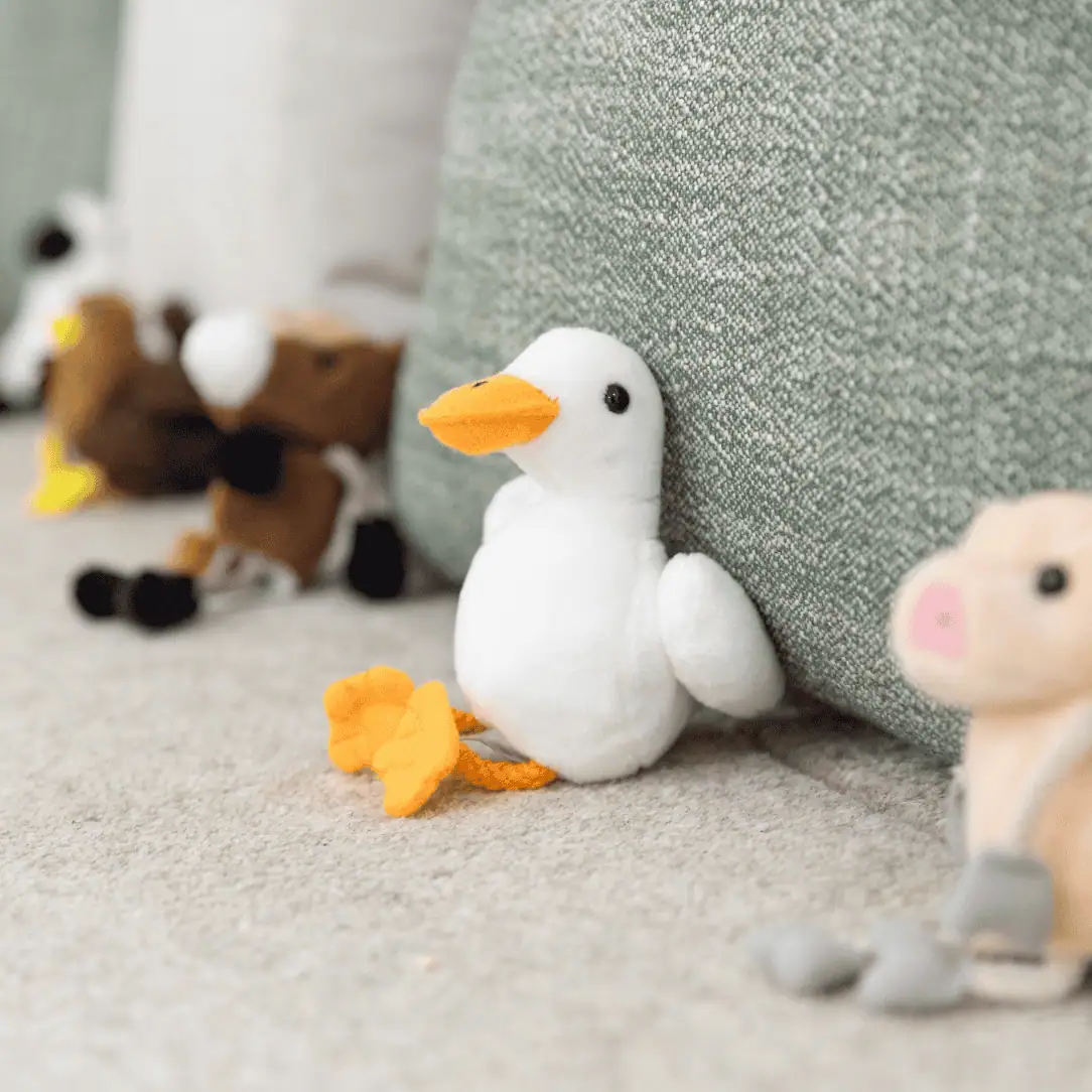 Soft plush animal toys on a cozy nursery floor, including a white duck with an orange beak, in a colorful and child-friendly daycare environment at Monkey Puzzle Day Nurseries.