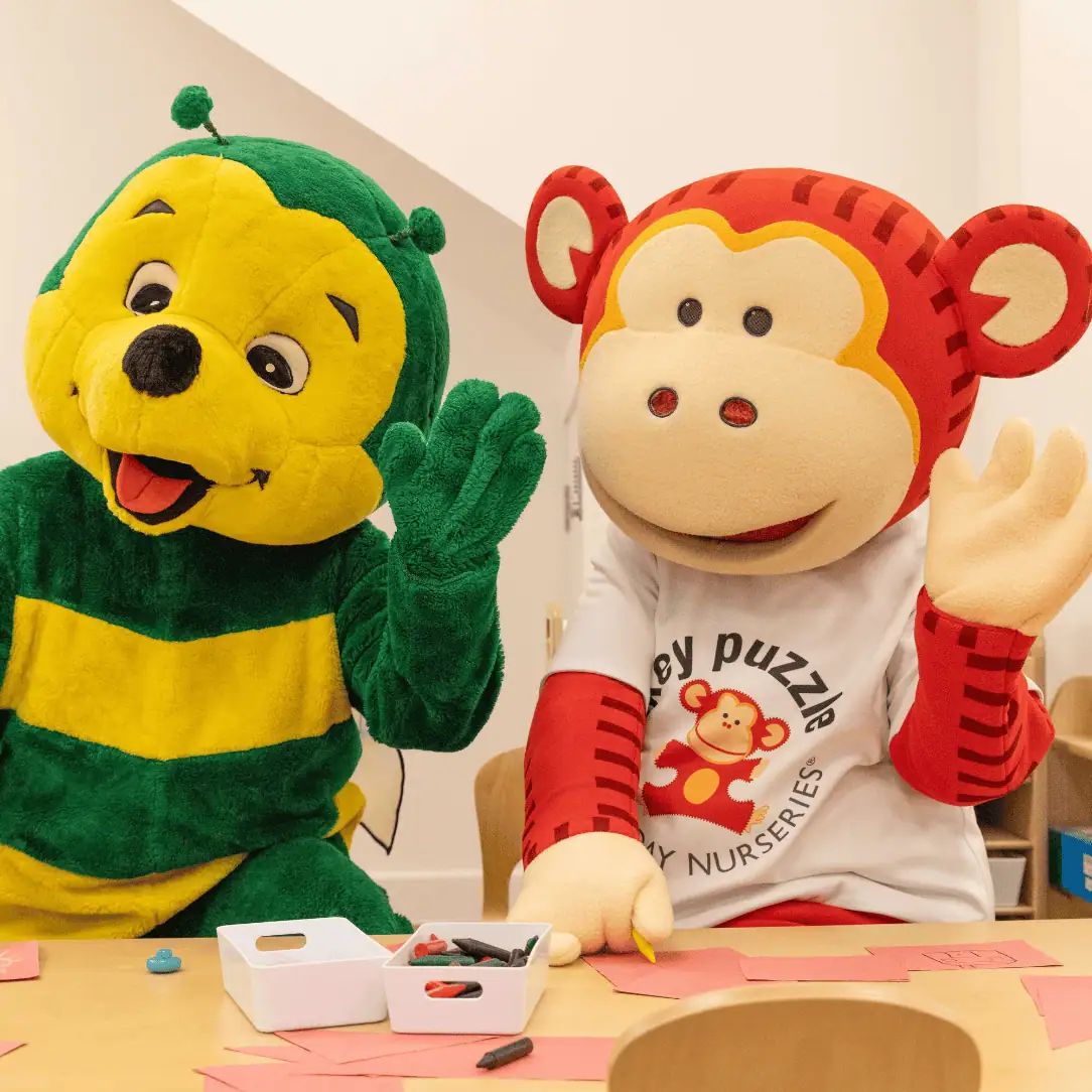 Colorful monkey and bee mascots at Monkey Puzzle Day Nurseries engaging kids in fun activities, promoting early childhood learning and play in a vibrant nursery environment.