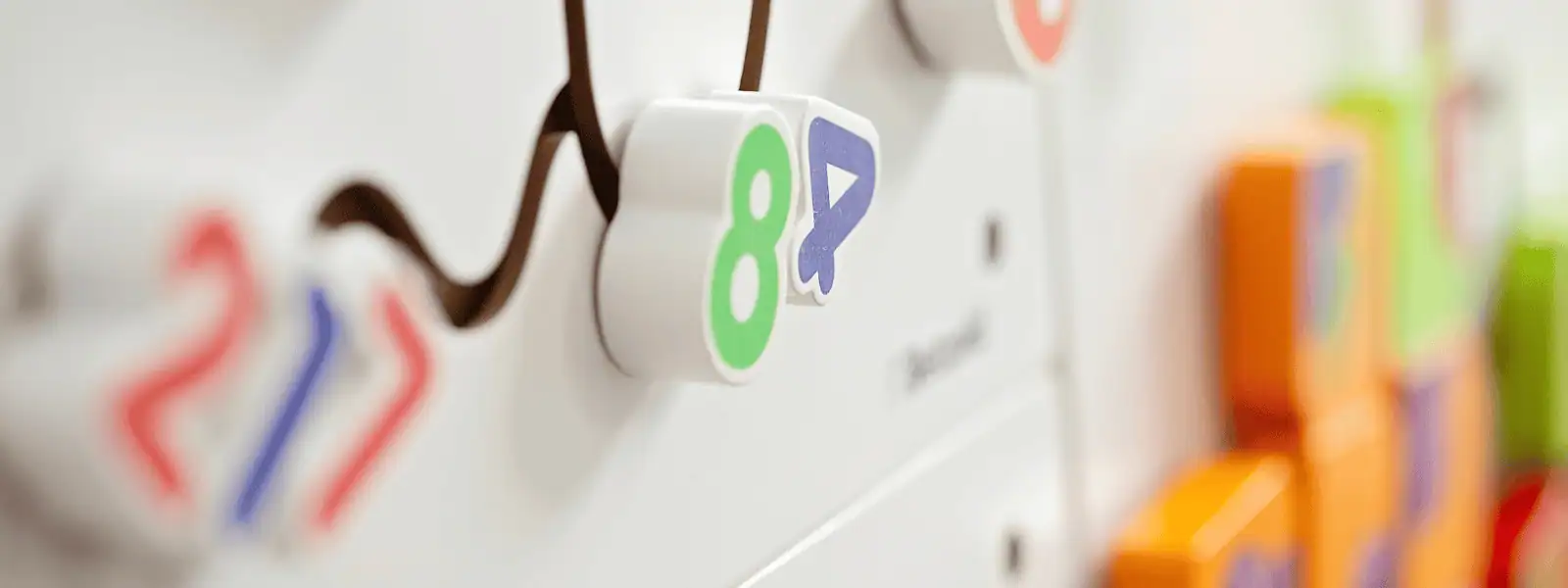 Colorful magnetic numbers on whiteboard at Monkey Puzzle Day Nurseries, promoting early childhood education and cognitive development.