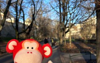 Monkey Puzzle Day Nurseries plush monkey mascot on a sunny outdoor pathway with leafless trees.