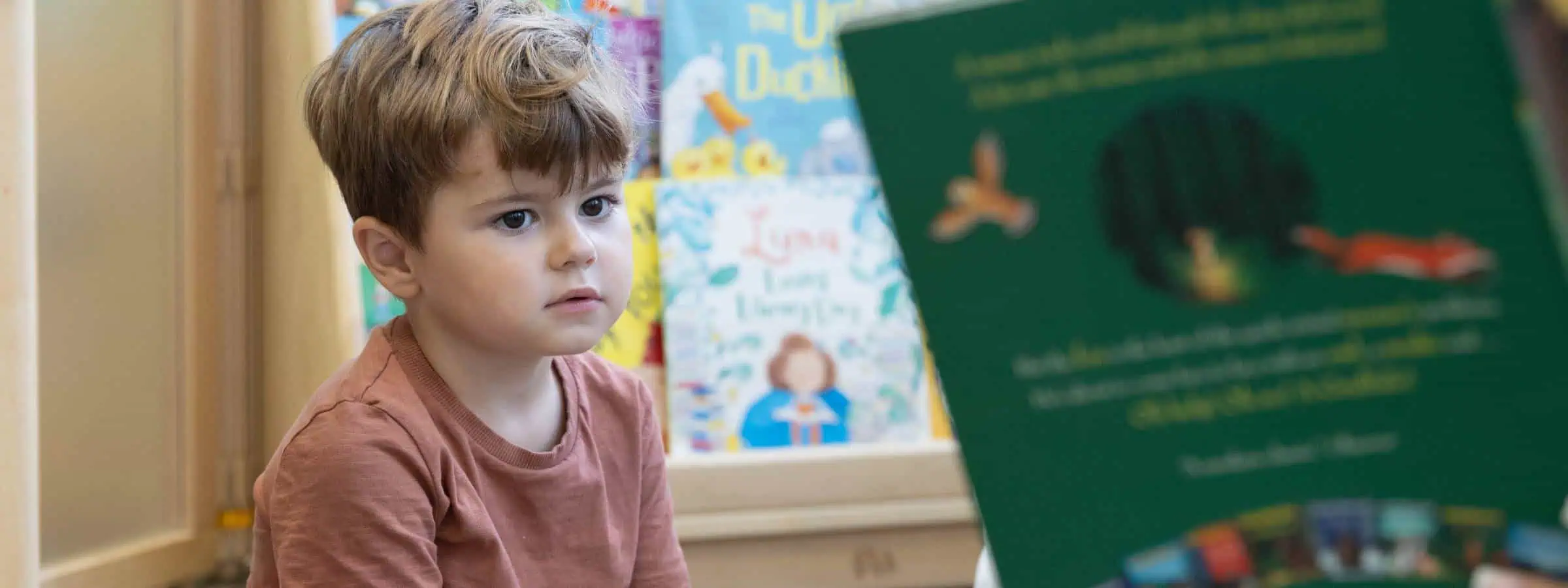 Young boy attentively listening during storytime at Monkey Puzzle Day Nurseries, fostering early childhood learning and development in a caring nursery environment.