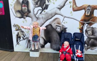 Colorful mural featuring cartoon-style jungle animals at Monkey Puzzle Day Nurseries, with two young children enjoying the playful environment. Perfect for early childhood education centers.