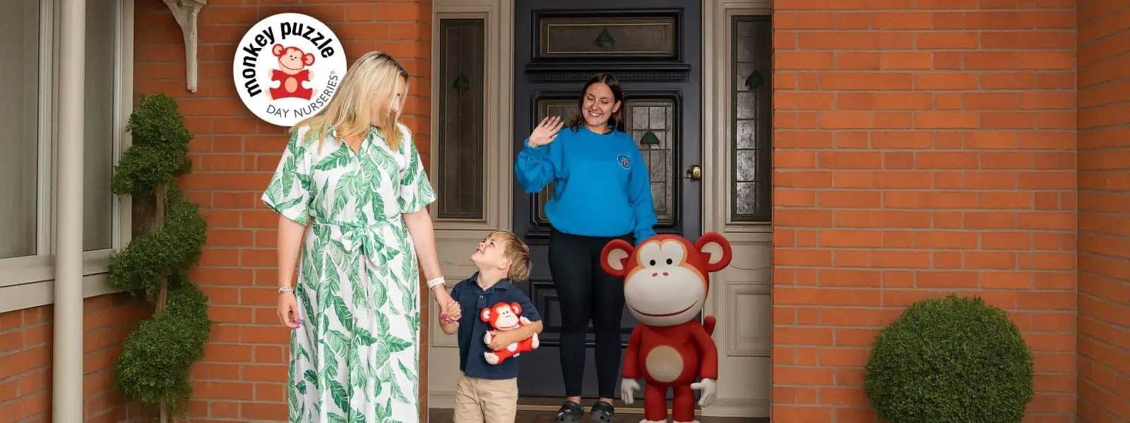 Bright, welcoming entrance of Monkey Puzzle Day Nurseries showing children, staff, and monkey mascots at the doorstep, emphasizing quality early childhood education and childcare services.