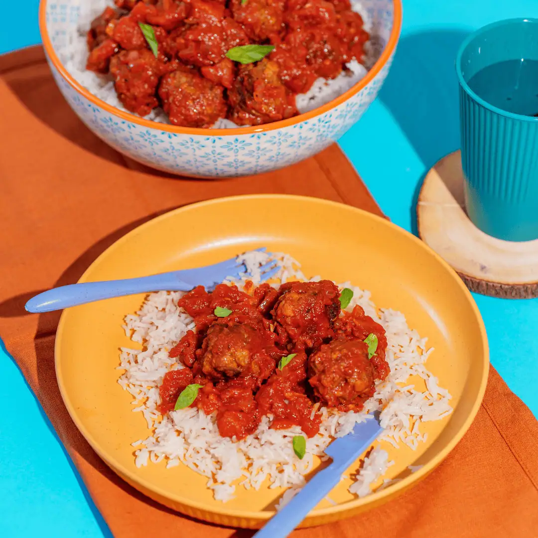 Vegetable beef meatballs served over rice with tomato sauce, colorful children's meal, healthy lunch option for preschool kids.