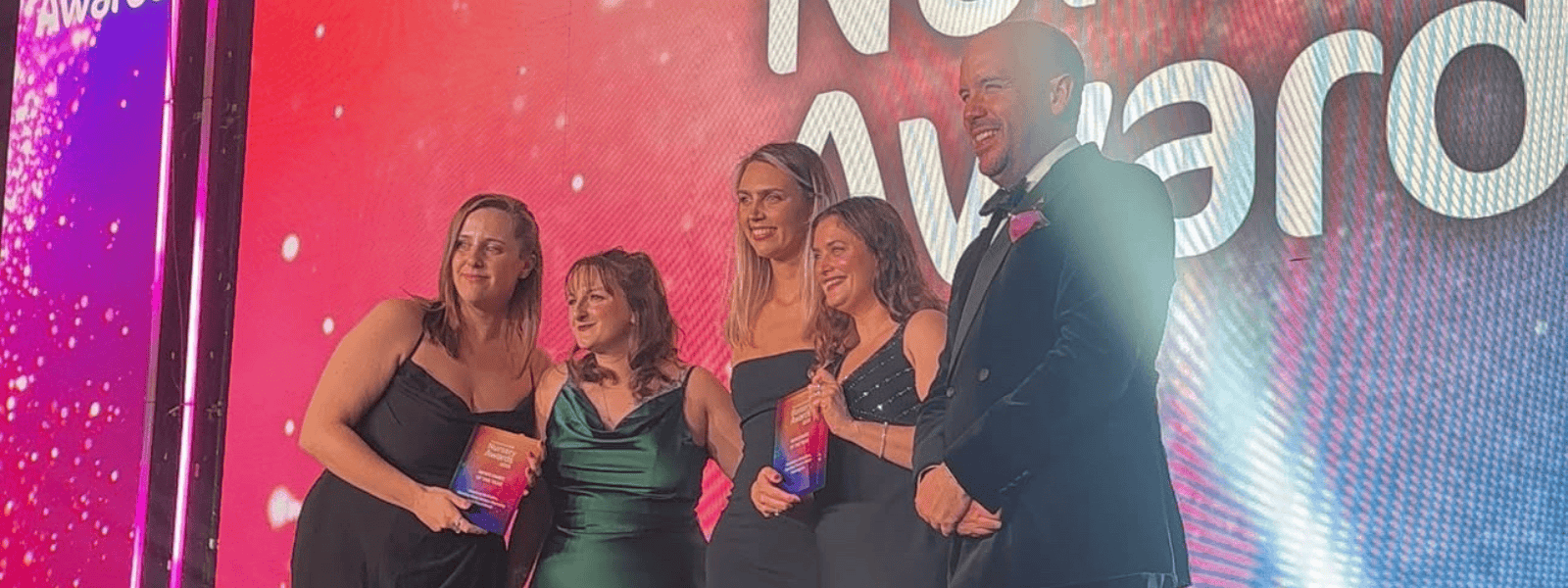 A group of happy children and staff celebrating success at Monkey Puzzle Day Nurseries.