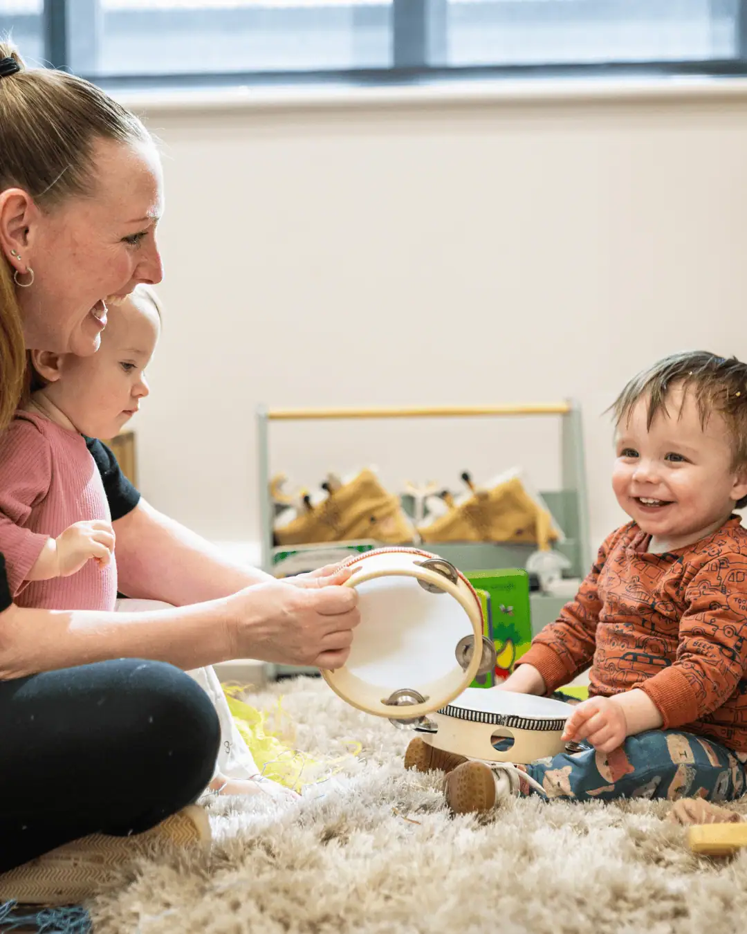 Child and caregiver engaging with musical toys in a nursery setting.