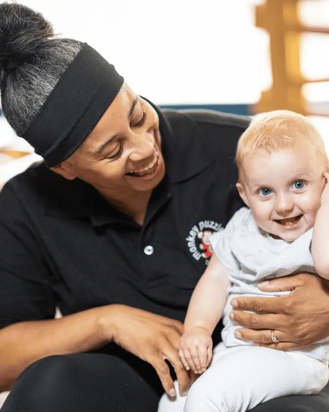 Smiling caregiver with a young child in a nursery setting, showcasing caring and safe environment for children's development.