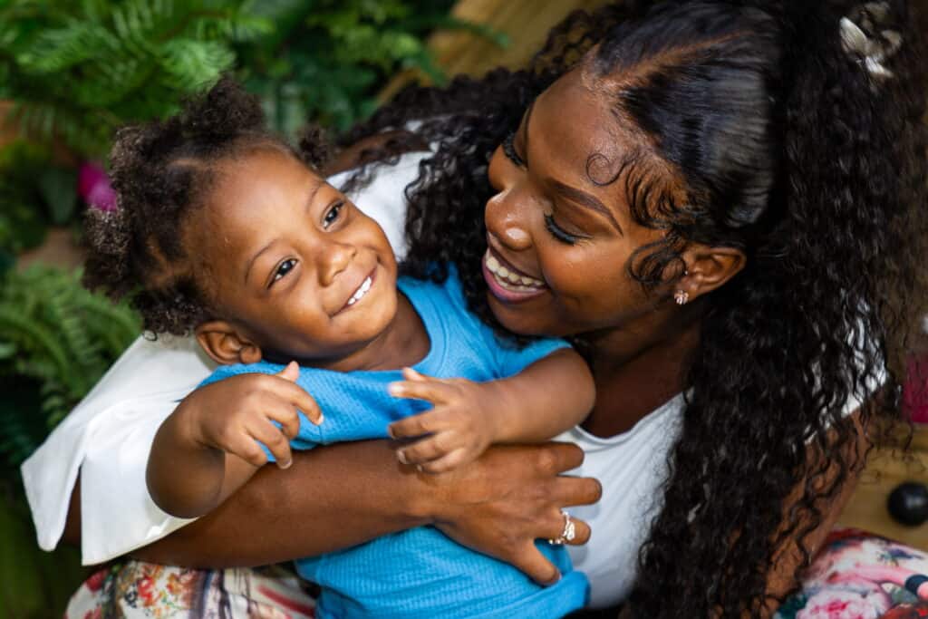 Happy Child and Caregiver at Monkey Puzzle Day Nur Joyful child and caregiver sharing a loving moment at Monkey Puzzle Day Nurseries, emphasizing caring environment for early childhood development.