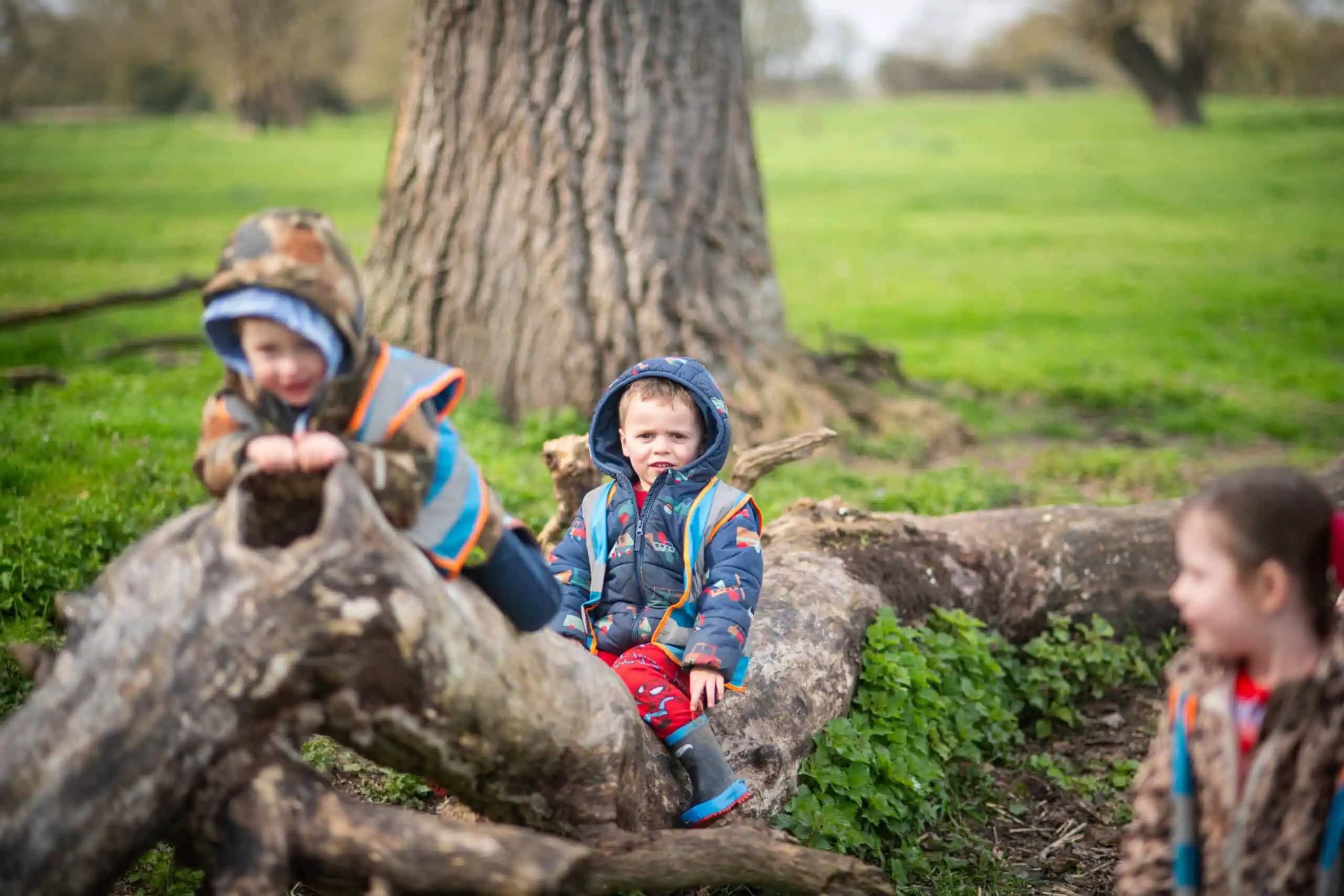 Children Playing Outdoors in Autumn Young children playing on a fallen tree in a park during autumn, enjoying outdoor activities and nature.